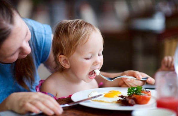 Young mother and her daughter having breakfast together